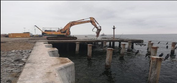 Excavadora con martillo hidráulico demoliendo un muelle